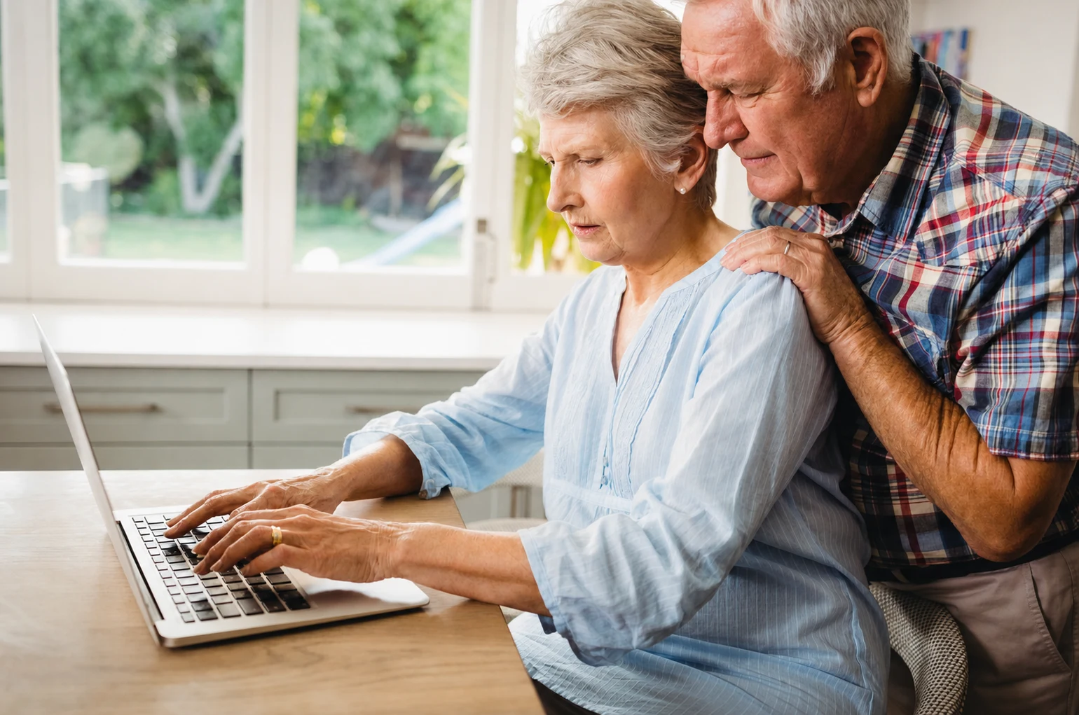 Casal a consultar um computador portátil em casa